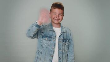 Toddler boy smiling friendly at camera and waving hands gesturing hello or goodbye, welcoming video