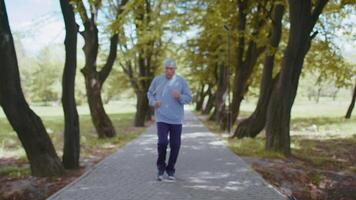 Motivated sport athletic retired senior old man running in park, grandfather checking pulse on arm video