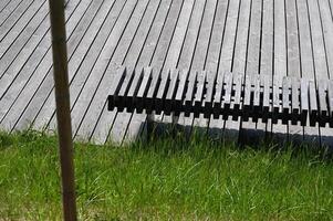 a bench sitting in the grass next to a wooden deck photo
