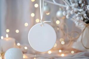 White blank round flat ceramic ornament tag with ribbon hanging in soft boho setup photo