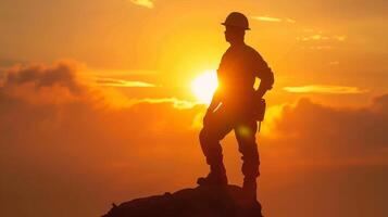 Silhouette of a construction worker standing on a mountain top at sunset, symbolizing success, achievement, and the future of infrastructure. photo
