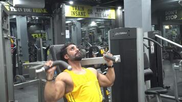 A boy using weights machine for arms at the gym video