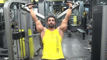 A boy using weights machine for arms at the gym video