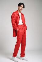 Confident Young Korean Man in Stylish Red Outfit. poses against a neutral background. photo