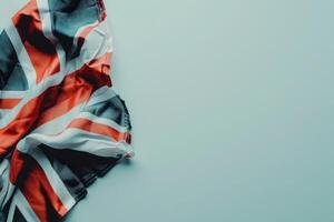 A neatly folded Union Jack flag rests on a smooth white background, displaying its vibrant red, white, and blue colors in a serene arrangement. photo