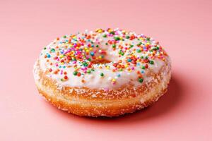 A deliciously glazed donut adorned with vibrant sprinkles rests elegantly against a soft pink background. photo