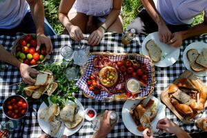 A group of friends enjoy a delightful picnic spread on a checkered blanket. They indulge in fresh bread, savory meats, and vibrant fruits, creating a joyful atmosphere of sharing and camaraderie. photo