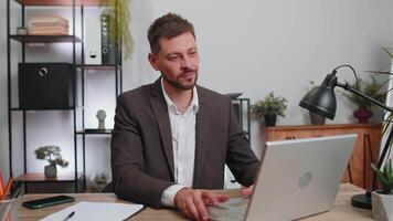 Businessman working on office laptop pointing to camera looking with happy expression making choice video