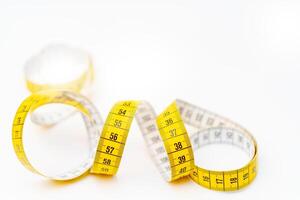 Yellow measuring tape on white background. Measurement of length and circumference. Lose weight and get fat. photo