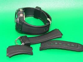 Photo of a damaged black watch strap on a green background
