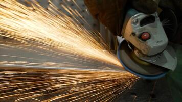A worker cuts, grinds and polishes a metal part with sparks in a workshop, close-up. Metal grinding, close-up. A worker cuts metal with a grinder, bright red sparks close-up. photo