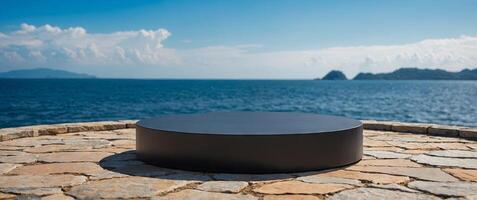 Empty round black podium on stone platform with sea island and blue sky background for product display. photo
