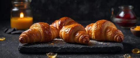 Delicious croissants freshly baked and accompanied by jam are presented on a dark stone background The enticing pastries offer an attractive copy space image. photo