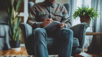 Man writing in notebook while sitting in cozy armchair photo