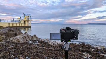 Closeup of modern mirrorless dslr camera recording beautiful scene of Blackrock, Salthill at sunset at Galway, ireland, technology concept background photo