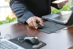 hand of businessman touching a computer mouse with laptop computer photo