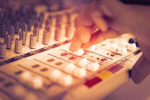 finger of engineer or music producer controlling sound recording studio mixing desk photo