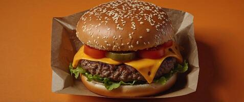 Big burger with cheese in a package on a bright orange background Fast food delivery Top view. photo