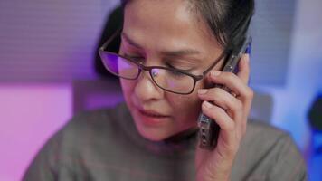 Close-up of Asian female programmer calling co-worker pointing and looking at multiple laptop screens to write code, having database system problems while working on development website or programming video