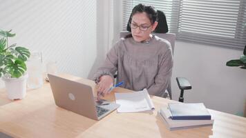 Close-up focuses on happy millennial woman working at computer with documents. Analyze paper reports Feeling satisfied with the research results distant working day video