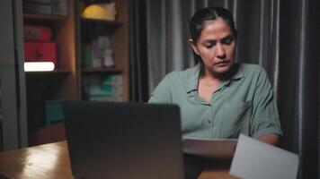lendo documento, ásia empresária trabalhando Difícil e preocupante às noite dentro a vivo quarto do a casa. problemas dentro projeto, trabalhando em computador portátil perda do o negócio a conceito do fadiga a partir de trabalhar. video