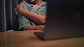 fechar-se do uma mão massageando uma dolorido braço e ombro a partir de trabalhar. mulher trabalhando às noite trabalhando usando computador portátil e tendo forte dor dentro ombro e braço, sedentário estilo de vida conceito. video