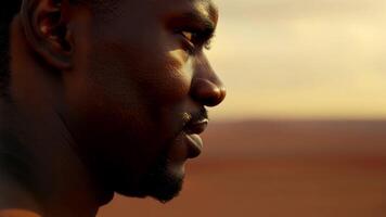 In a closeup shot the strong and chiseled features of an African American man are highlighted against the backdrop of the vast and unforgiving desert landscape.. video