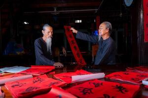old scholars writing calligraphy at lunar new year. Calligraphy is a popular tradition during Tet holiday. Text in photo mean Happy New Year and Peace.