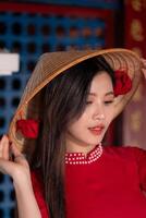 Vietnamese girl with Ao Dai dress standing in traditional house of Vietnam. Text in photo mean best wishes to family, happiness, prosperity, health. Tet holiday and New Year.