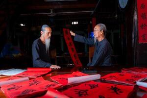 old scholars writing calligraphy at lunar new year. Calligraphy is a popular tradition during Tet holiday. Text in photo mean Happy New Year and Peace.