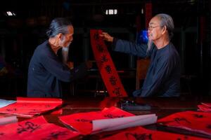 old scholars writing calligraphy at lunar new year. Calligraphy is a popular tradition during Tet holiday. Text in photo mean Happy New Year and Peace.