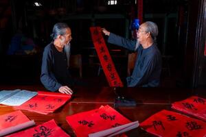 old scholars writing calligraphy at lunar new year. Calligraphy is a popular tradition during Tet holiday. Text in photo mean Happy New Year and Peace.