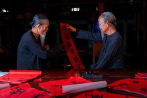 old scholars writing calligraphy at lunar new year. Calligraphy is a popular tradition during Tet holiday. Text in photo mean Happy New Year and Peace.