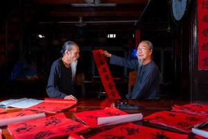 old scholars writing calligraphy at lunar new year. Calligraphy is a popular tradition during Tet holiday. Text in photo mean Happy New Year and Peace.