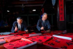 old scholars writing calligraphy at lunar new year. Calligraphy is a popular tradition during Tet holiday. Text in photo mean Happy New Year and Peace.