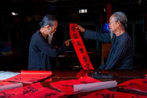 old scholars writing calligraphy at lunar new year. Calligraphy is a popular tradition during Tet holiday. Text in photo mean Happy New Year and Peace.