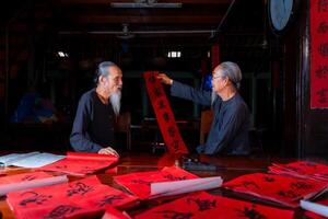 old scholars writing calligraphy at lunar new year. Calligraphy is a popular tradition during Tet holiday. Text in photo mean Happy New Year and Peace.