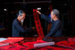 old scholars writing calligraphy at lunar new year. Calligraphy is a popular tradition during Tet holiday. Text in photo mean Happy New Year and Peace.