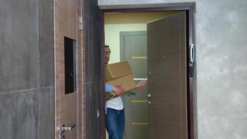 Young man moving in new home. Freelancer or programmer is having fun with cardboard boxes in new house at moving day video