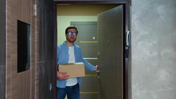 Young man moving in new home. Freelancer or programmer is having fun with cardboard boxe in new house at moving day video