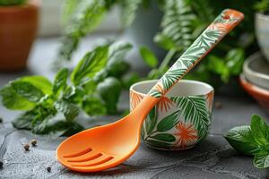 An orange and green patterned serving spoon rests against a floral patterned bowl on a dark textured surface photo