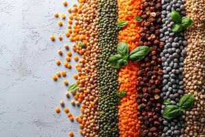 Colorful arrangement of various types of dried split peas and lentils with green basil leaves on a concrete background photo