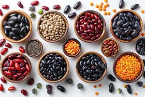 Wooden bowls filled with various types of beans and lentils on a whitewashed background photo