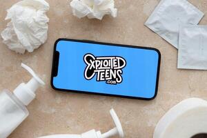 KYIV, UKRAINE - JANUARY 23, 2024 ExploitedTeens adult content website logo on display of iPhone 12 Pro photo
