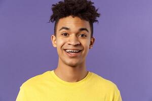 Close-up portrait of cheerful smiling man looking happy, express enthusiastic optimistic emotions, seeing something pleasant and interesting, standing purple background photo