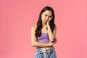 Portrait of stylish young popular girl sitting in self-isolation covid-19 quarantine and have nothing to do, lean on palm staring camera bored and uninterested, feel boredom, pink background photo