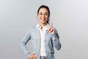 Education, studying and online classes concept. Rule number one. Cheerful pretty asian girl explaining exercise to class, raising index finger, pointing up, add a suggestion or making point, smile photo