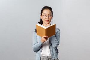 Education, teachers, university and schools concept. Intrigued smart good-looking asian student prepare for test exam, reading her lecture notes in notebooks, checking schedule in planner, thoughtful photo