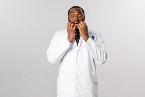 Portrait of scared, embarrassed african-american man gasping and look afraid, jumping from fear as kid in ER frightened him, hold hands near mouth, standing afraid over grey background photo