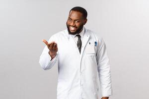 Pleased to meet you, tell me your problem. Portrait of polite and friendly, charismatic african-american doctor inviting patient to sit and explain what bothered them, working in hospital or clinic photo